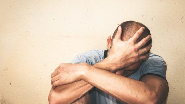 un hombre se tapa la cabeza con los dos brazos