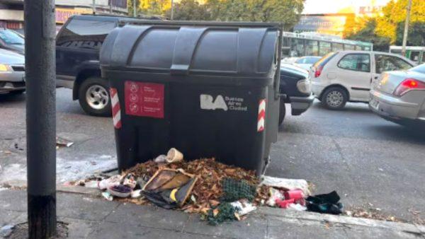 contenedor de basura en la calle, con basura tirada en el piso