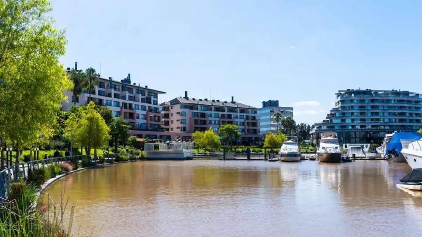 Bahía residencial de Nordelta con edificios de departamentos y barcos amarrados en el canal.
