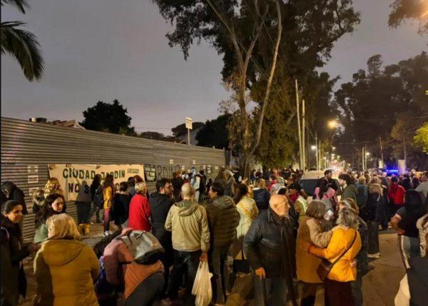 grupo de personas protestando frente a un portón gris