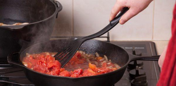 Una mano revuelve con un utensilio negro salsa que está sobre una sartén. (Crédito: Getty)