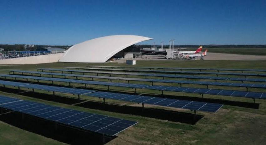 Un aeropuerto con aviones de fondo y paneles solares en primer plano