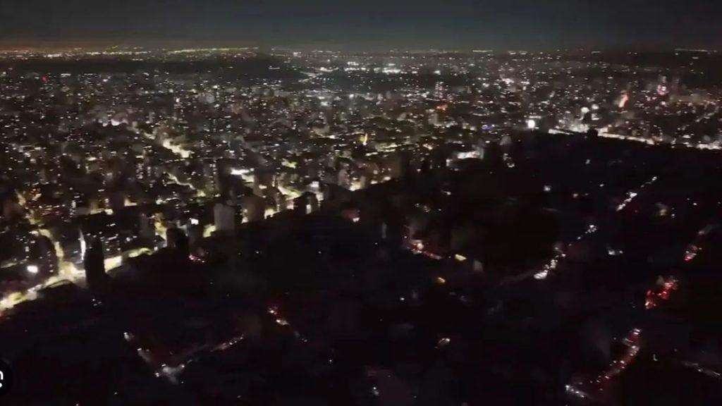 una imagen aérea del AMBA de noche dividida a la mitad, de un lado totalmente a oscuras y del otro lado toda iluminada