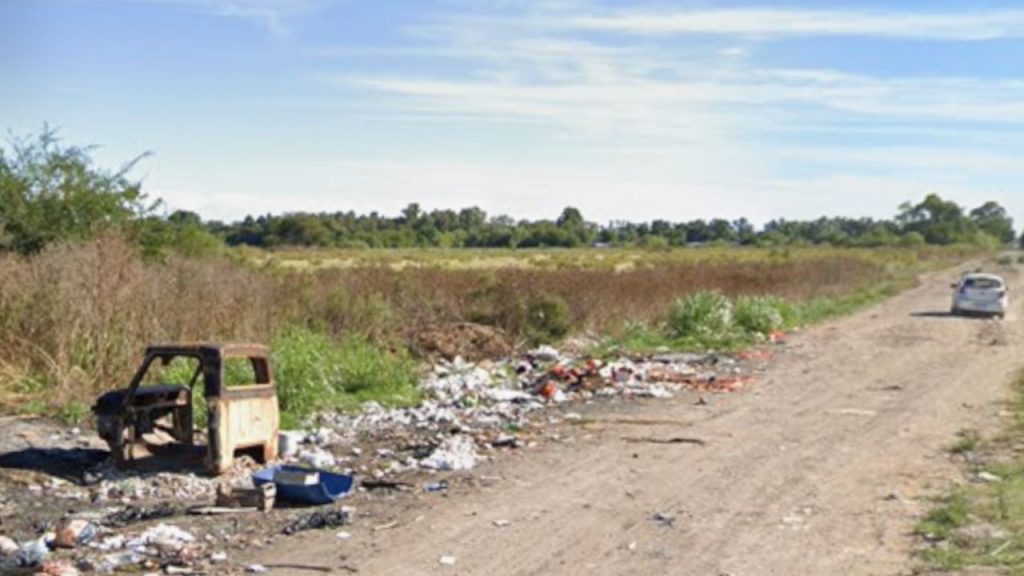 restos de basura y una autoparte al costado de un camino de tierra. De fondo, un auto en movimiento