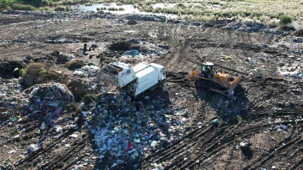 dos vehículos pesados recogen residuos en el basural de Luján