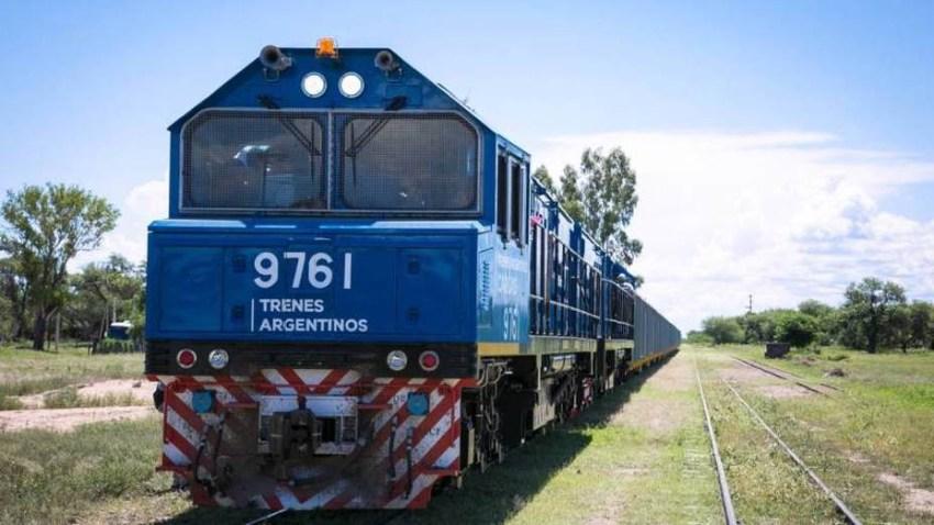 Frente de un tren azul estacionado en un campo verde con árboles de fondo