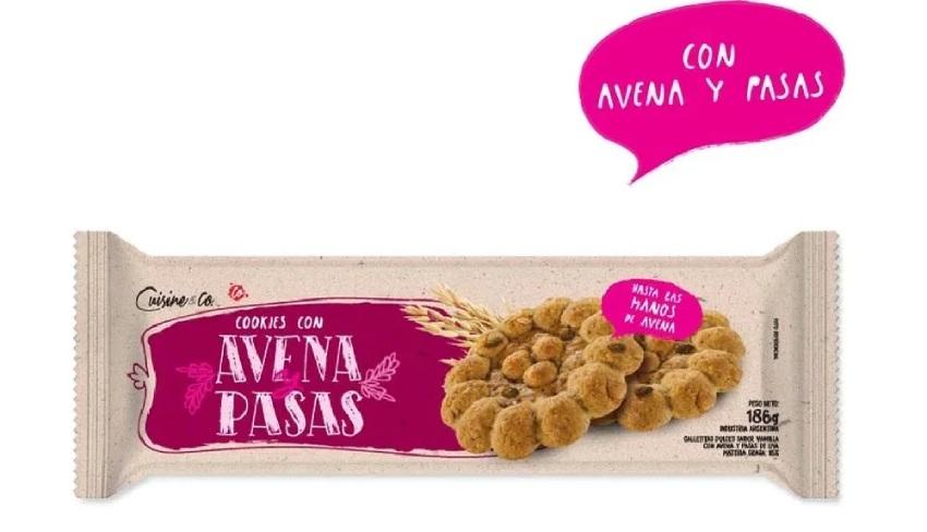Envoltorio de galletitas Cuisine & Co. "Cookies con Avena y Pasas" de 186g. Muestra la ilustración del paquete beige y violeta con dos galletitas con forma de flor y un globo de texto en rosa que dice "Con avena y pasas"