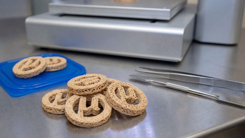 7 galletitas de plástico PET distribuidas en dos grupos de 5 y 2 sobre la mesa de acero de un laboratorio