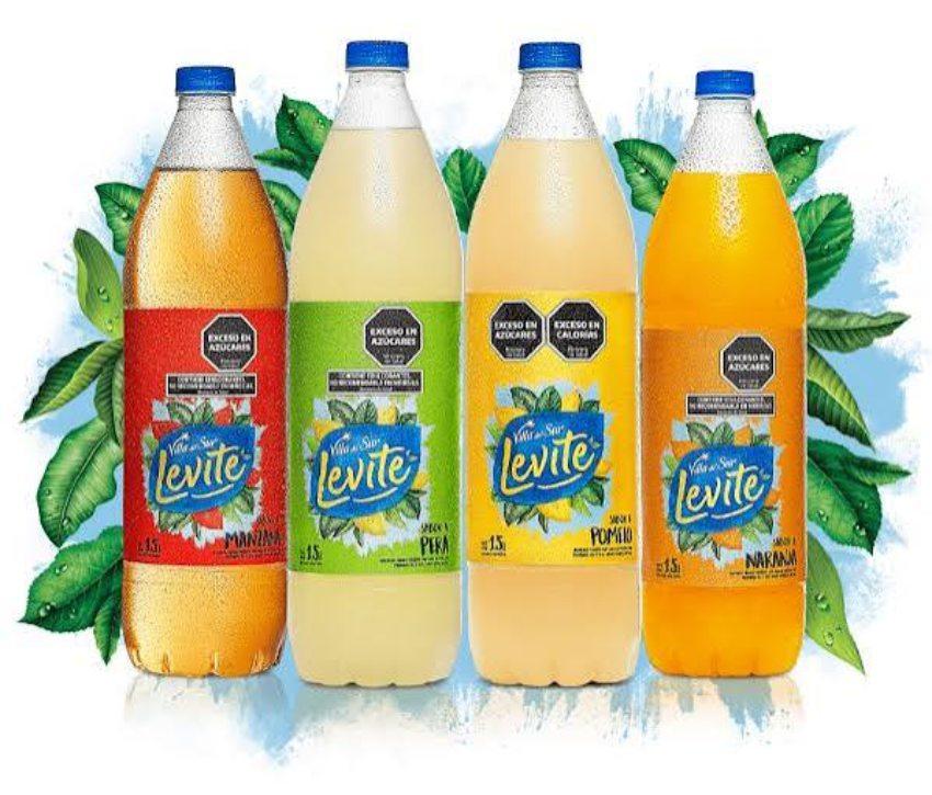 Cuatro botellas de agua saborizada Villa del Sur Levité de 1,5 litros en fila (sabores manzana, pera, pomelo y naranja) sobre un fondo blanco con hojas verdes.