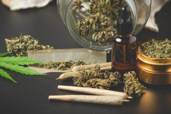 Varios cigarrillos de marihuana, con cogollos y un frasco al fondo.