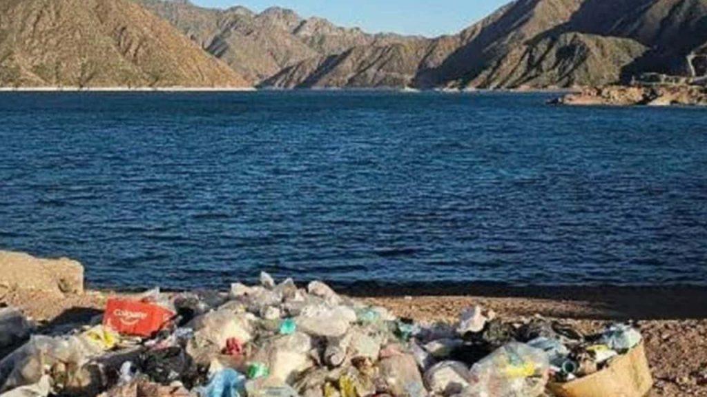 un río con montañas de fondo y en la otra orilla lleno de basura