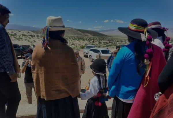 Un grupo de mujeres y niños está parados delante de unas camionetas.