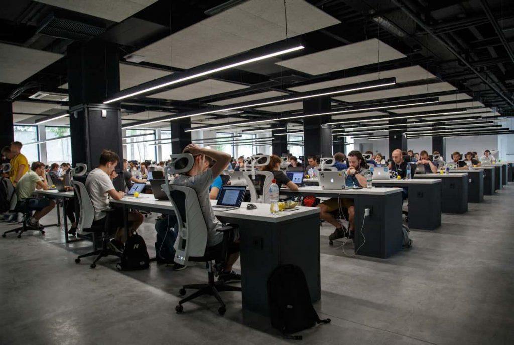 muchas personas dentro de una oficina sentadas en mesa y cada uno con sus respectivas computadoras trabajando. Imagen: Unplash