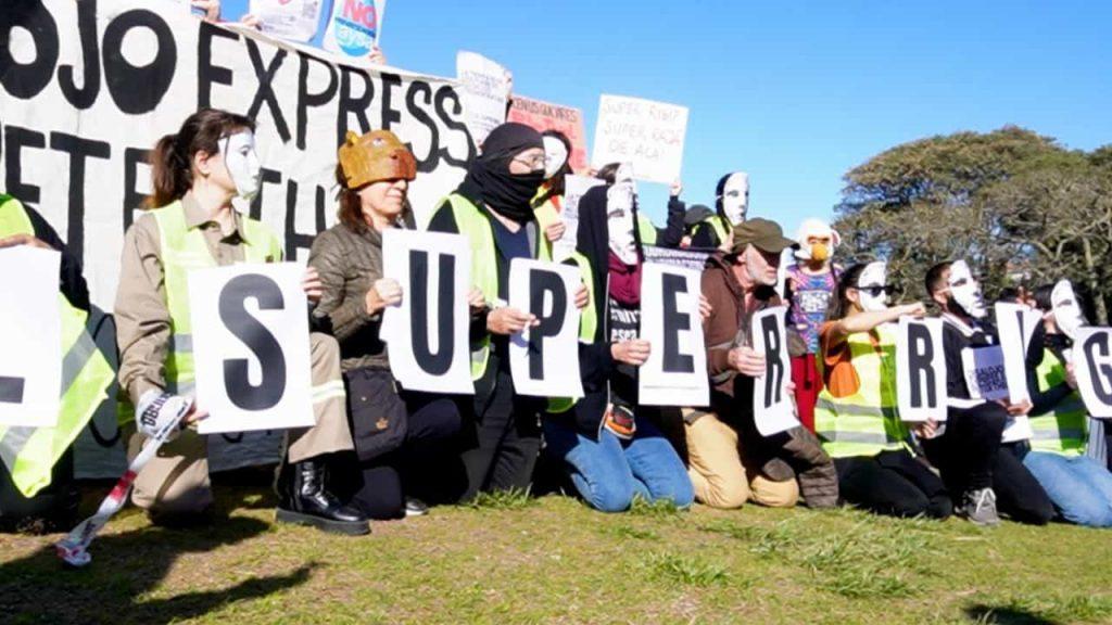 manifestantes con la cara tapada reclaman contra la presencia de Peter Thiel en Argentina mostrando distintos mensajes en pancartas