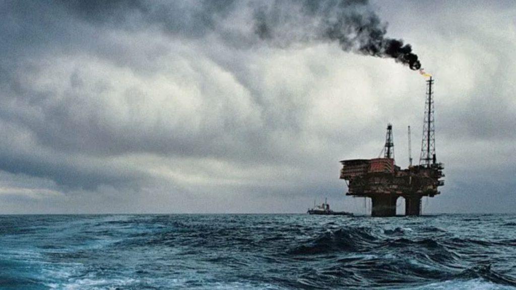 en medio de un mar enorme, se observa una plataforma de petróleo a lo lejos