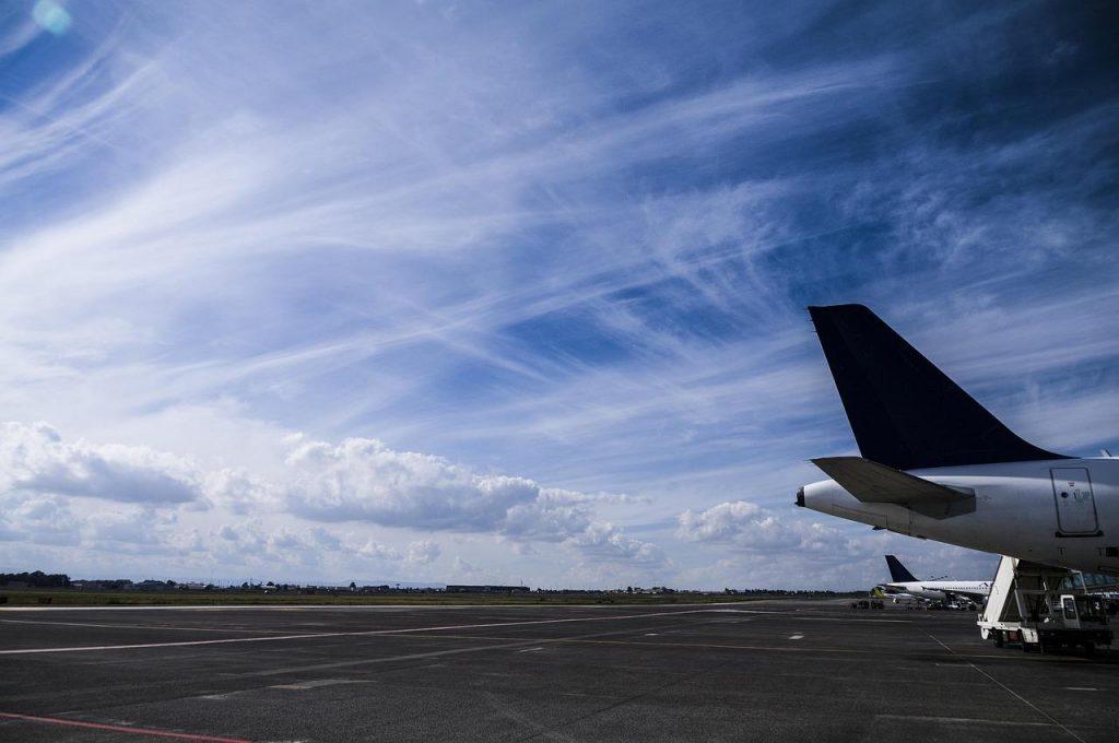 Cola de un avión sobre una pista, detrás cielo azul.