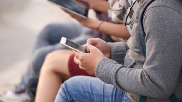 Solo se observa el cuerpo de distintas personas que están con el celular en la mano en posición sentados. Imagen: Archivo Economía Sustentable