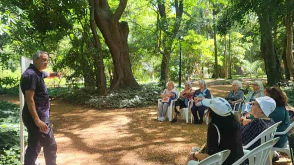 un hombre dándo una charla de prevención contra el calor frente a un grupo de jubilados en una plaza de CABA