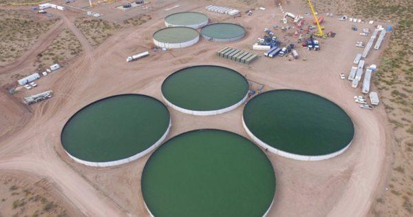 Vista aérea de grandes piletas circulares de almacenamiento de agua en una instalación de extracción petrolera en el desierto
