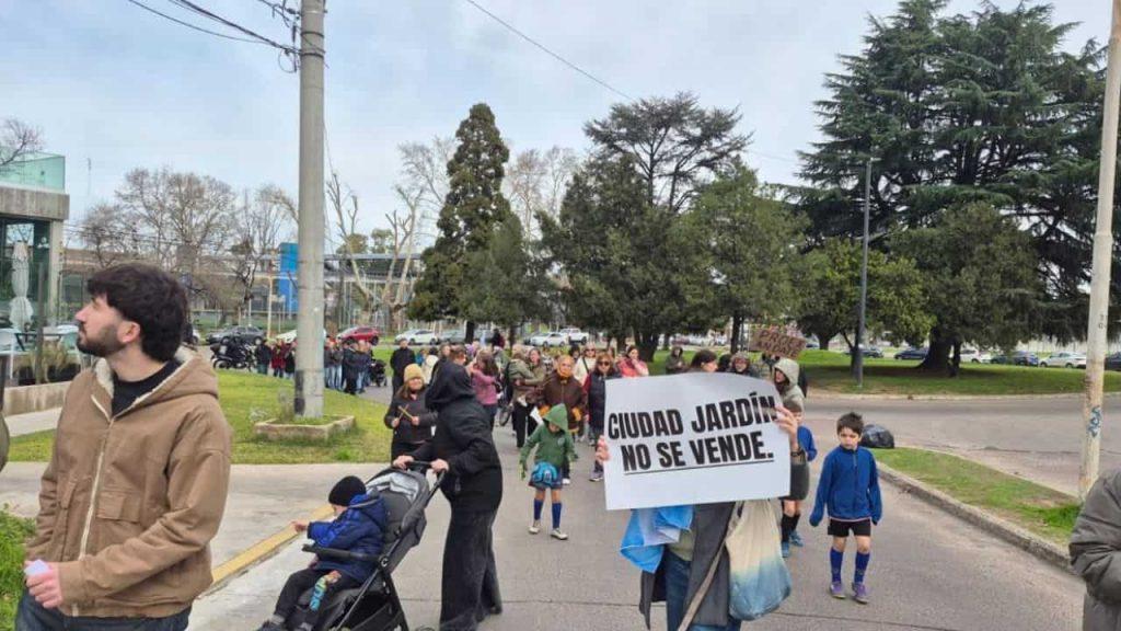 En medio de un grupo de vecinos, uno sostiene un afiche que dice Ciudad Jardín no se vende