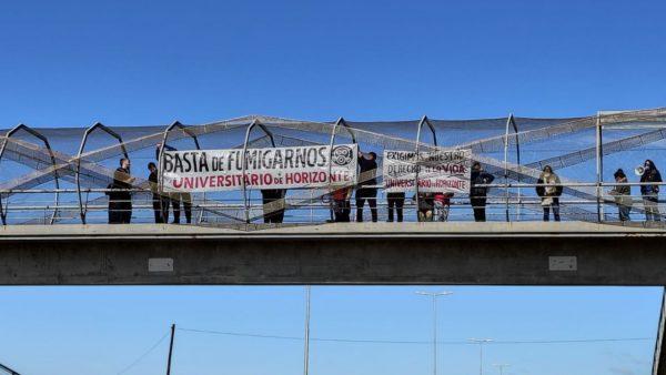 Personas sostienen pancartas sobre un puente con mensajes contra los agrotóxicos