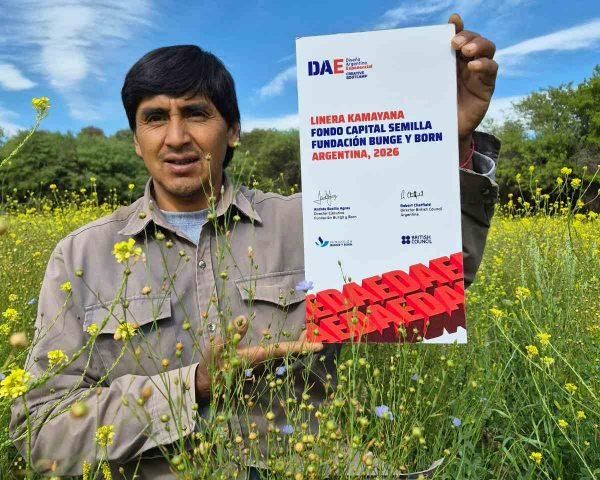 Productor de lino sosteniendo un certificado de reconocimiento entre flores de cultivo