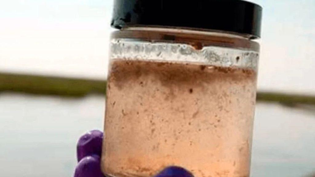 Frasco con una muestra de agua turbia y sedimentos, utilizada para ilustrar la contaminación por arsénico en el agua