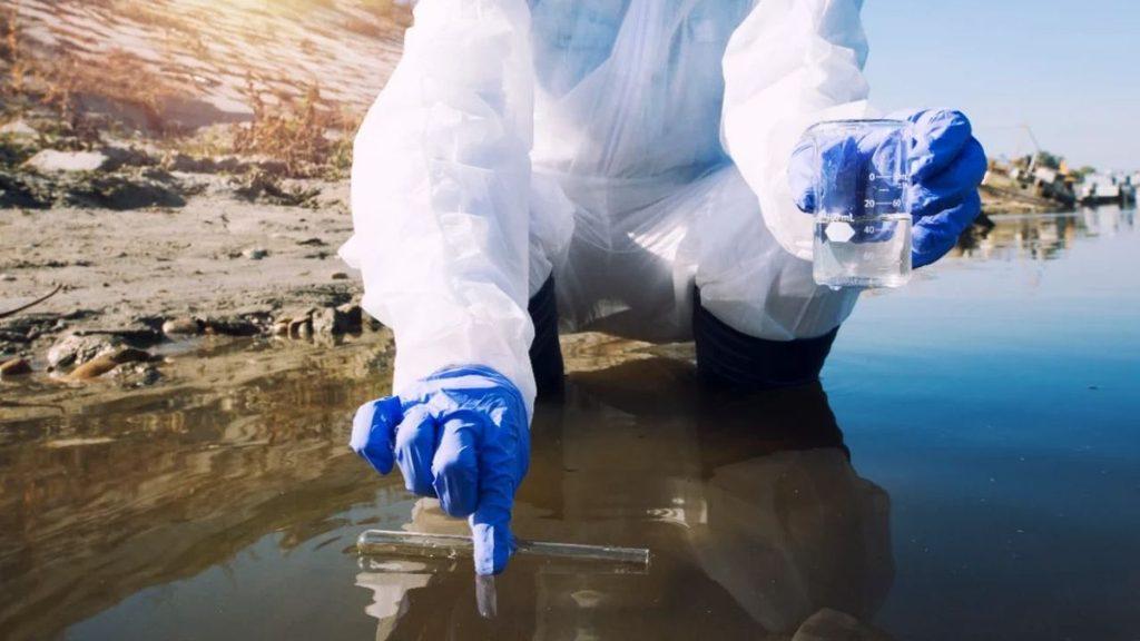 Un especialista toma muestras de agua en la orilla de un cuerpo de agua para analizar su calidad y detectar posibles contaminantes