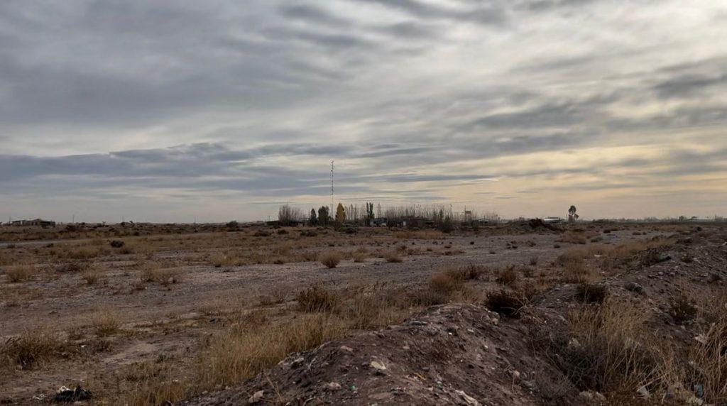 Vista de un terreno árido con suelo removido, vegetación seca y restos dispersos, en las inmediaciones de un predio vinculado al acopio de residuos petroleros de COMARSA, en Neuquén