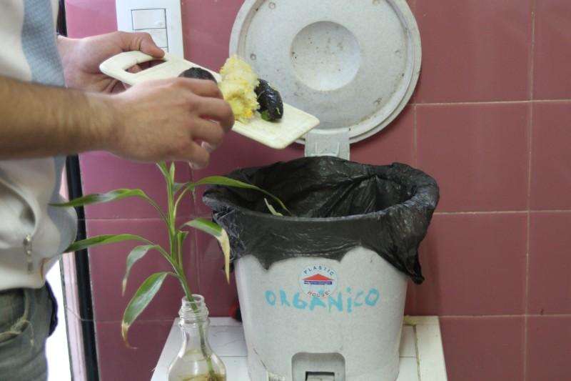 Una persona tira residuos en un tacho que dice "orgánico".