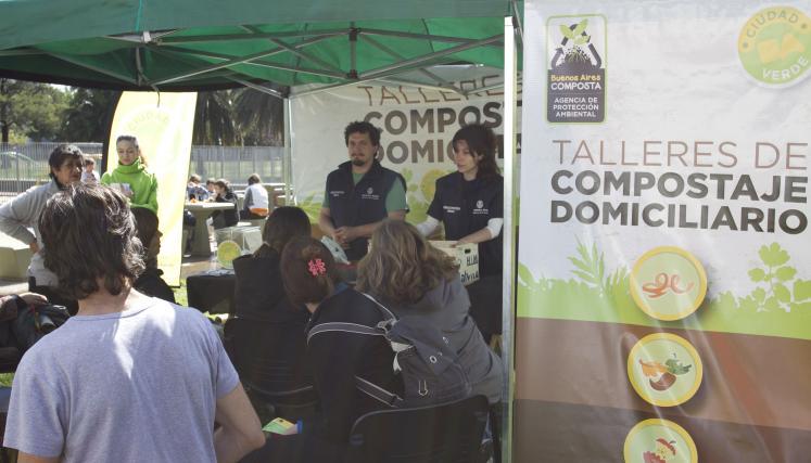Taller al aire libre sobre compostaje domiciliario bajo un cenador con la marca de Buenos Aires Composta.