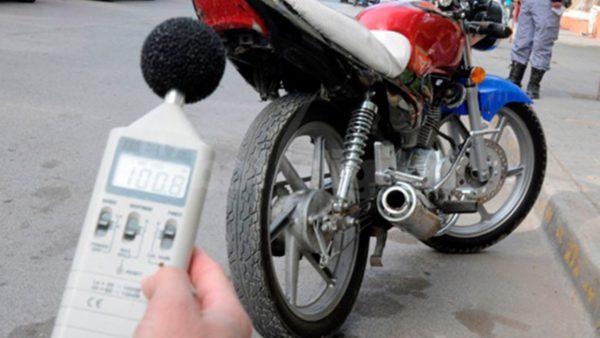 una moto estacionada y una mano con un dispositivo que mide los volúmenes del ruido