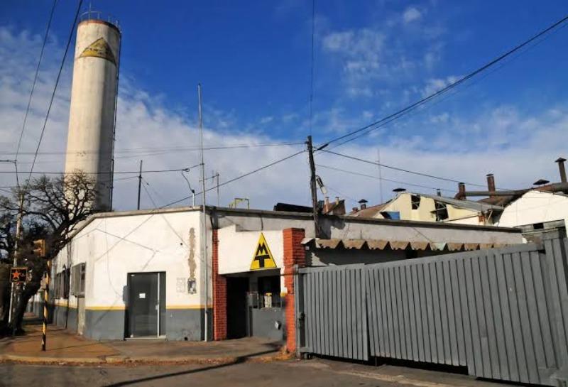 Fachada exterior y gran torre cilíndrica de la ex fábrica Metalúrgica Tandil bajo un cielo despejado