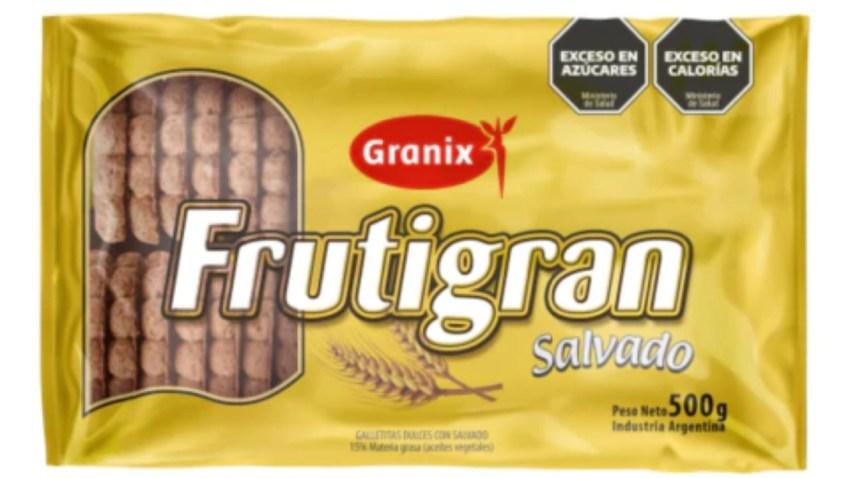 Paquete amarillo de 500 gramos de galletitas Frutigran Salvado de la marca Granix. En la parte frontal se observa la marca, una ilustración de espigas de trigo y los octógonos negros de advertencia nutricional por exceso en azúcares y calorías