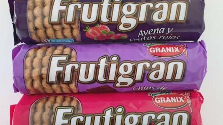 Tres paquetes de galletitas Frutigran apilados verticalmente. El paquete superior es morado oscuro de avena y frutos rojos; el del medio es violeta claro sabor chips de chocolate de la marca Granix; y el inferior es un paquete de color rosa fuerte