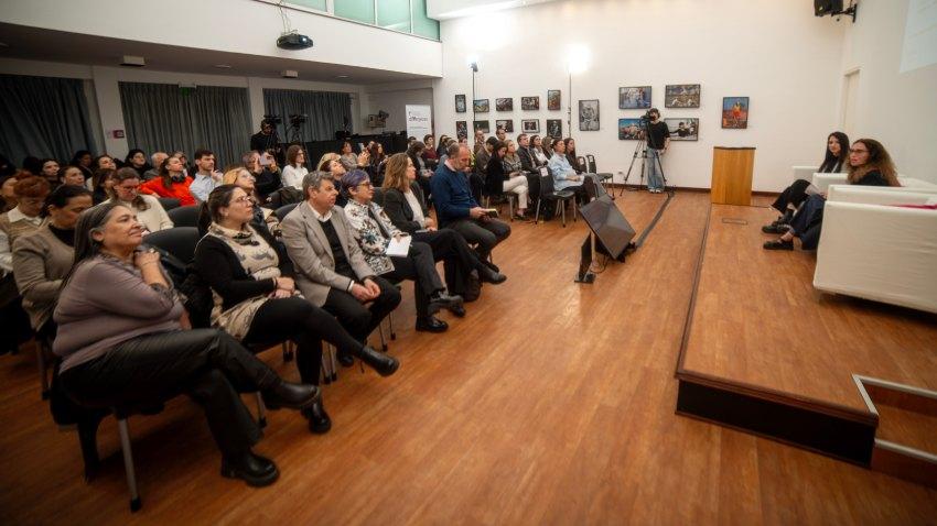Un grupo de personas sentadas miran hacia adelante donde hay otras dos presentando un informe.