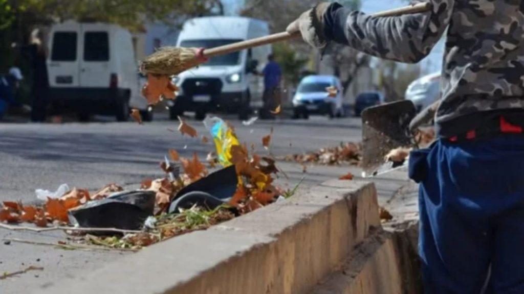 una persona recoleta hojas secas en la calle en Mendoza