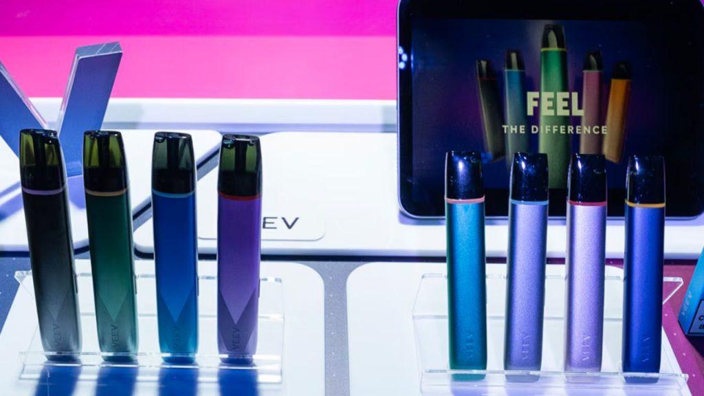 Un soporte con 8 vapeadores y una pantalla táctil de fondo que dice "sentir la diferencia".