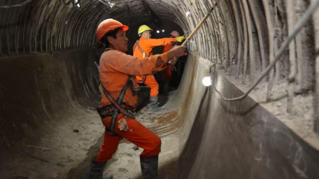 Operarios con ropa de seguridad trabajan en el interior de un túnel subterráneo durante la construcción de una obra hidráulica