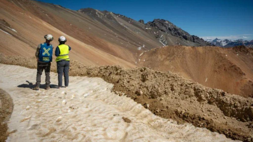 Dos trabajadores con cascos y chalecos de seguridad observan un terreno montañoso en una zona de exploración minera en Mendoza