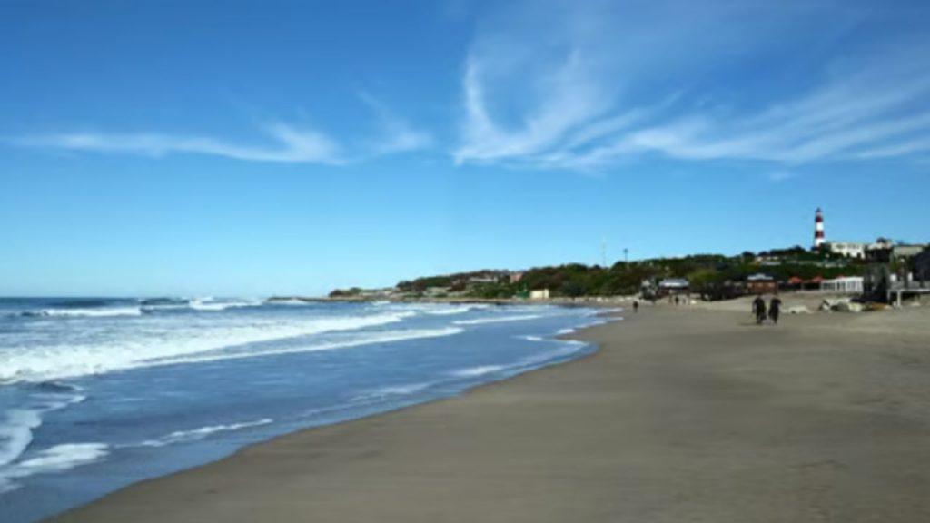 arena, mar y, de fondo, el faro de Mar del Plata