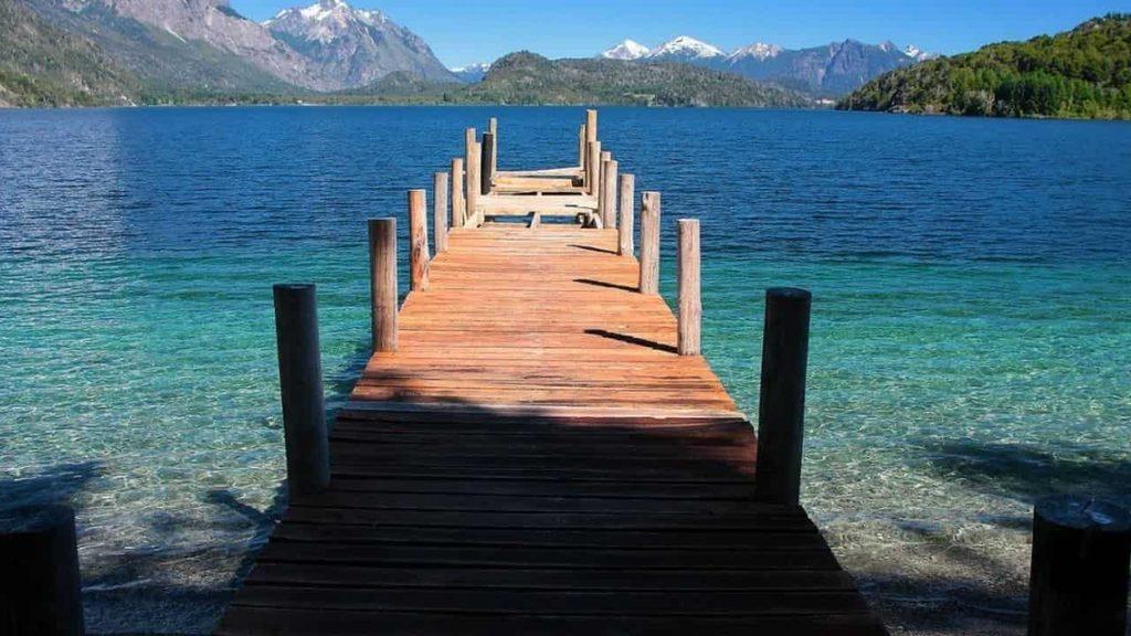 Muelle de madera sobre las aguas cristalinas del lago Moreno, rodeado de montañas y bosques de la Patagonia argentina