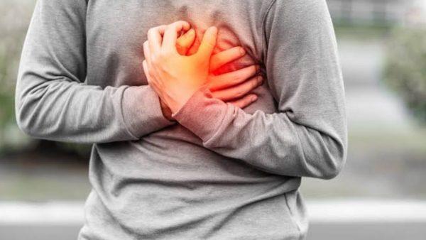 Persona con las manos sobre el pecho y una zona resaltada en rojo que representa un posible dolor cardíaco