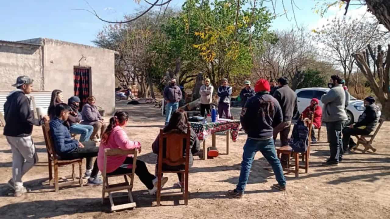 Integrantes de una comunidad rural de Santiago del Estero reunidos al aire libre frente a una vivienda, en un encuentro comunitario