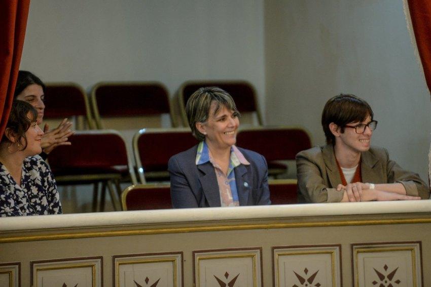 Laura Sánchez, madre de Ema Bondaruk, sonríe sentada junto a un joven en el palco del Senado de la Provincia de Buenos Aires durante una sesión.