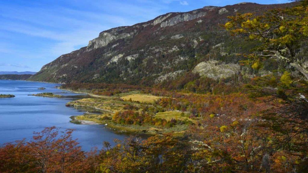 Paisaje del Parque Nacional Tierra del Fuego con un lago, montañas rocosas y vegetación nativa en tonos otoñales